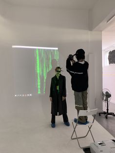 two people standing in front of a screen with green images projected on the wall behind them