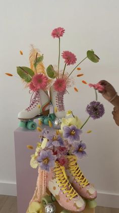 a vase filled with flowers and shoes on top of a table