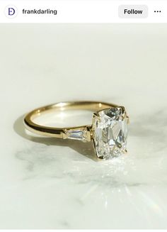 an engagement ring with two baguets on the side and a diamond in the middle