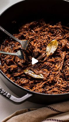 a pot full of shredded meat with spoons in it