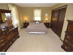 a bed sitting in a bedroom next to a dresser and mirror with two lamps on top of it