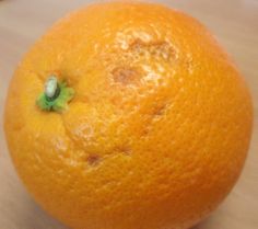 an orange sitting on top of a wooden table