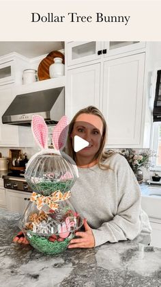 a woman sitting in front of a counter holding a basket filled with candy and bunnies