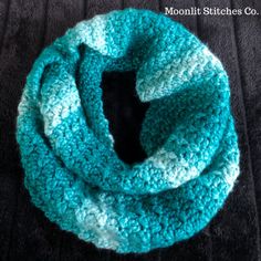 a blue and white crocheted scarf on top of a black blanket