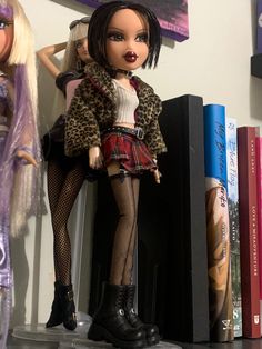 a doll is posed next to some books