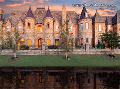 a large castle like building sitting on top of a lush green field next to a body of water