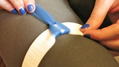 a woman with blue nail polish on her nails is sitting in a gray chair while holding a toothbrush