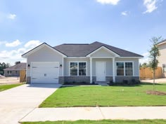 a white house sitting in the middle of a grass covered yard with two garages