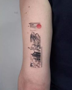 a person with a tattoo on their arm that has an image of mountains and houses