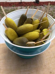 a bowl filled with pickles sitting on top of a table next to a wooden stick