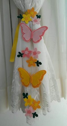 a white dress with yellow and pink butterflies on it, hanging from a curtain rod