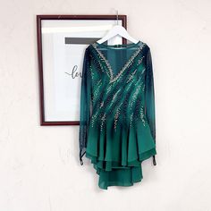 a woman's green dress hanging up on a wall next to a framed photograph