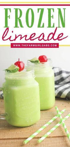 two jars filled with green liquid and topped with cherries, on top of a wooden table