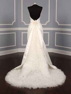 the back of a wedding dress on display in a room with blue walls and wood flooring