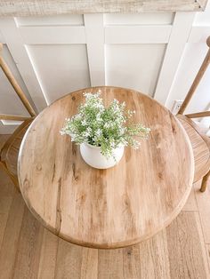 a small potted plant sitting on top of a wooden table next to two chairs