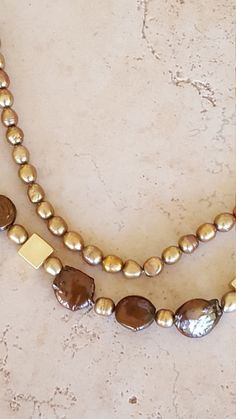 "Swarovski Pearl and Shell Necklace.  This beauty has 2 strands.  A mixture of chain and beading. The inner strand is chain with all swarovski pearls in a golden tone and measures to 20\".  The outer layer is a combination of chain and swarovski pearl, shell and gold plated metal beads and measures to 24\".  From elegance to casual, wear this with any outfit. Materials; Swarovski Pearls Shell Beads Gold Plated Metal Square Beads Gold Plated Toggle Clasp Gold Plated Chain Always a winner with pea Gold Double Strand Pearl Necklace, Gold Double Strand Pearl Necklace For Formal Occasions, Formal Gold Double Strand Pearl Necklace, Gold Double Strand Pearl Necklaces, Gold Multi-strand Pearl Charm Necklace, Gold Multi-strand Pearl Necklaces, Gold Multi-strand Pearl Necklace, Gold Pearl Beaded Necklace Single Strand, Gold Pearl Necklace With Beaded Chain