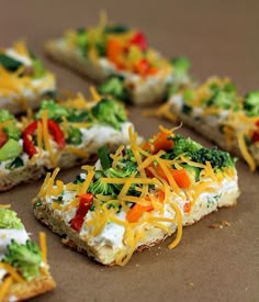 several pieces of pizza with cheese and vegetables on them sitting on a brown table top