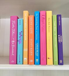 a row of colorful books sitting on top of a white shelf