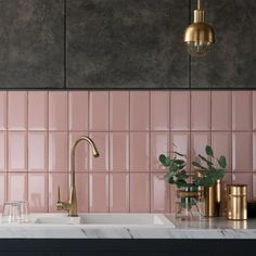 a kitchen with pink tiles and gold fixtures on the countertop, along with brass accents