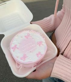 a person holding a pink cake in a plastic container