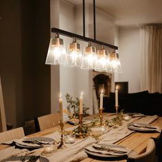 a dining room table is set with place settings and lit candles in the centerpieces