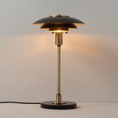 a lamp that is on top of a white surface with a black base and gold trim