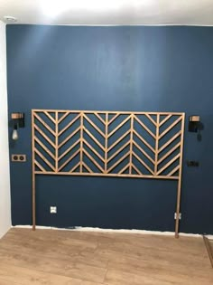 an empty room with a blue wall and wooden headboard on the floor, in front of a wood floor