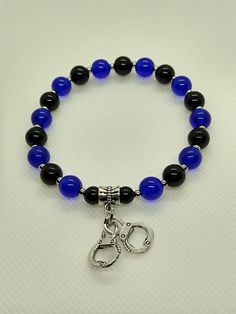 You will love the beauty in this beaded stretch bracelet designed with 8mm blue and black glass round beads, silver spacer beads, along with a police handcuff theme charm.  This beaded bracelet is designed exclusively by BeadsDesignedbyRenea and may not be copied.  Please review the photo of the size of beads.  This bracelet is approximately 7 to 7 1/2" and will stretch. Matching earrings are available in another listing (see photo above).  This listing is for the bracelet only. Be sure and check out other designs now available of this theme.  My shop offers combined shipping.  Select multiple items to purchase on one invoice and pay one flat fee.  This is a great deal for shoppers!! All items in my shop intended for adults. All items in my shop contains small parts that may pose a choking Police Bracelet, Police Jewelry, Handcuff Bracelet, Hand Cuff Bracelet, Chandler Az, Bracelet Blue, Bracelet Ideas, Beaded Stretch Bracelet, Blue Bracelet