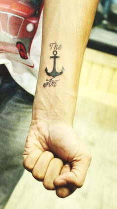 a man's arm with an anchor tattoo on his left wrist and the word, `