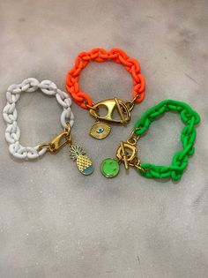 Three different handmade bracelets in similar summer philosophy with acrylic chains and different central charms as pendants. An Evil Eye charm at orange chain, a smile charm at green bracelet, and finaly a pineapple ath the white bracelet. You can choose between 3 different colors with their unique central charms. Wear them all together or separetely as well. In Christina Christi Jewels store you can see more than 35 designs in Women's Bracelets. You can have them in 2-4 Days with DHL EXPRESS S Trendy Adjustable Chain Bracelet For Beach, White Plastic Jewelry For Beach, Adjustable Chain Bracelets For Beach, Trendy Multicolor Chain Bracelet For Gift, Trendy Green Chain Bracelet As Gift, Trendy Green Chain Bracelet For Gift, Gold Chain Bracelets For Beach, Handmade Plastic Jewelry For The Beach, Trendy White Bracelets With Lobster Clasp