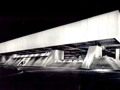 an old black and white photo of the outside of a building at night with lights on