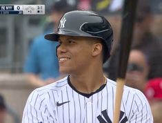 a baseball player is smiling and holding a bat in his hand while wearing a new york yankees uniform