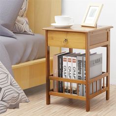 a small wooden table with books and a cup on it next to a bed in a bedroom