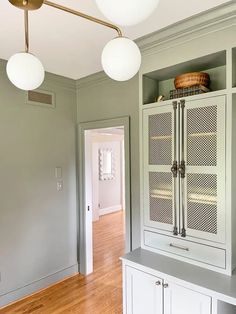 a kitchen with white cabinets and wood flooring in the middle of an empty room