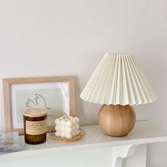 a table with a lamp, candle and other items on it next to a framed photograph