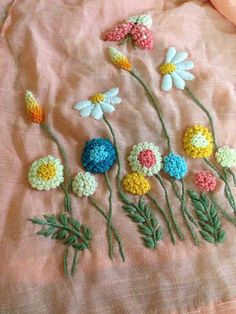 crocheted flowers are arranged on a pink sheet that is laying on a bed