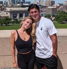 a man and woman standing next to each other in front of a cityscape