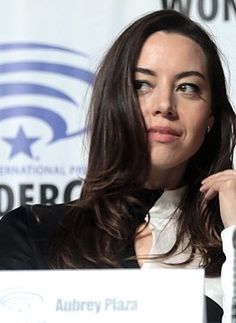 a woman sitting at a table in front of a microphone with her hand on her shoulder