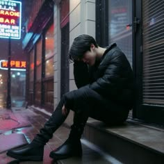 a person sitting on a ledge in the rain