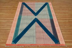 a multicolored area rug with fringes on top of wooden floor next to wood flooring