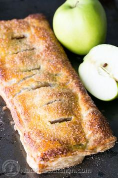 an apple pie next to two green apples