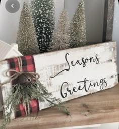 a wooden sign that says seasons's greetings with pine trees in the background