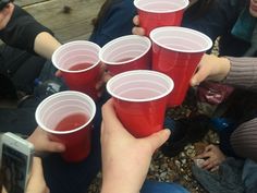 several people holding red cups in their hands