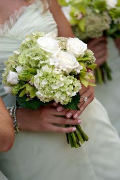 the bridesmaids are holding their bouquets with green and white flowers