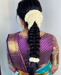 a woman with long black hair wearing a purple and blue saree, braided into a ponytail