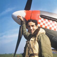 a man standing in front of an airplane with his hand on the back of it