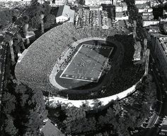 an aerial view of a football stadium in black and white, with trees surrounding it