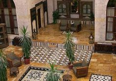 an indoor area with potted plants and tile flooring in the center, surrounded by arched doorways