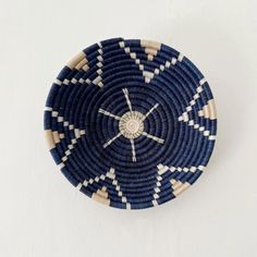 a blue and white woven basket hanging on the wall with a clock in it's center