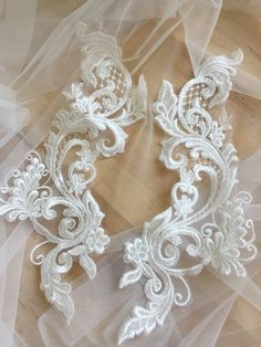 two white lace appliques on a piece of sheer tulle with an intricate design